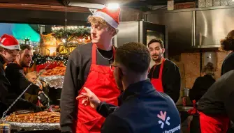 Mensen met kerstmutsen en rode schorten aan het werk bij een kraam