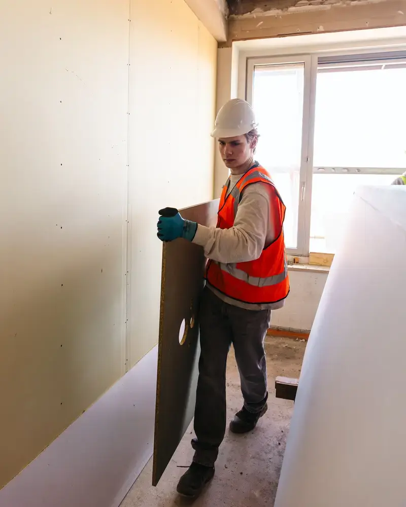 Medewerker met helm plaatst een plaat in een kamer in aanbouw