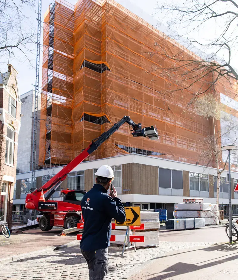 Medewerker van Actueel Personeel voor een gebouw in de steigers met een hoogwerker