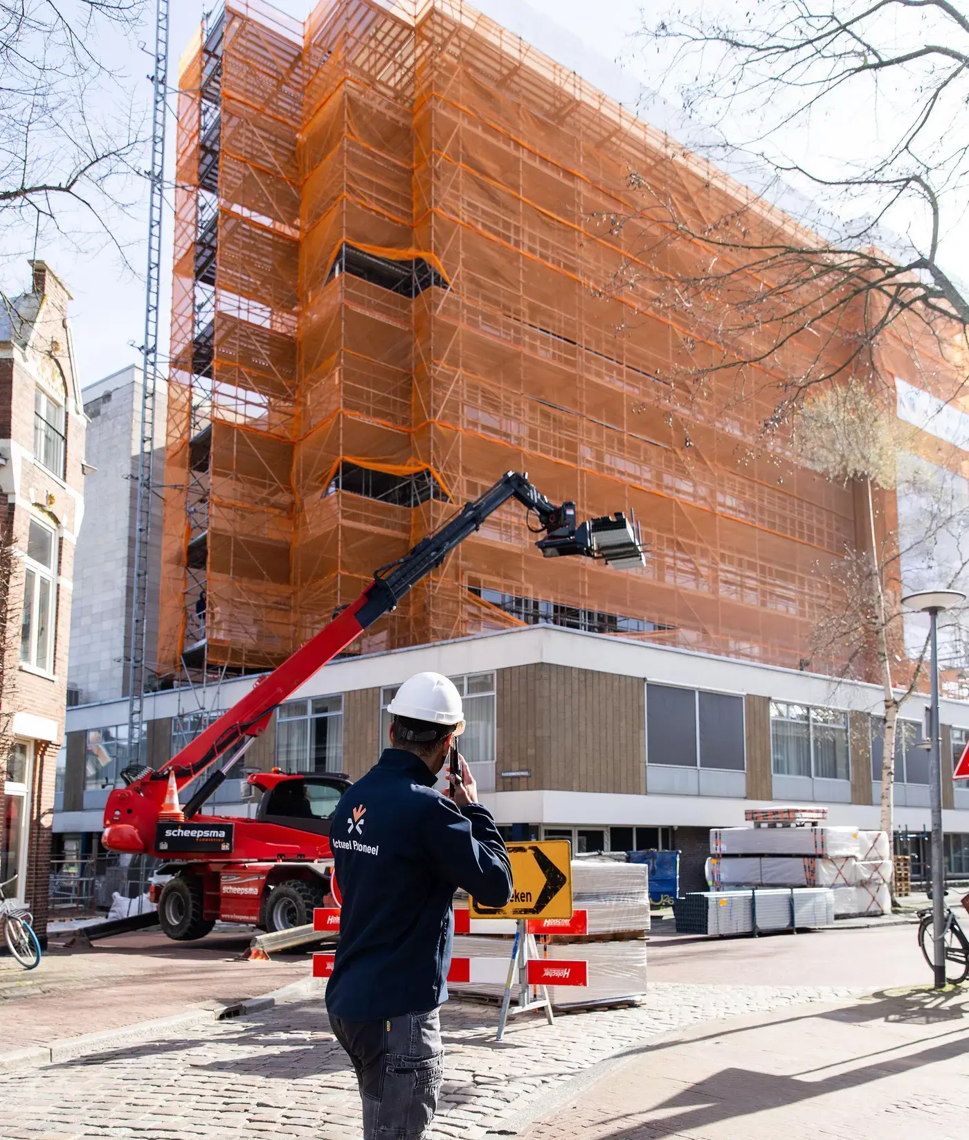 Medewerker van Actueel Personeel voor een gebouw in de steigers met een hoogwerker