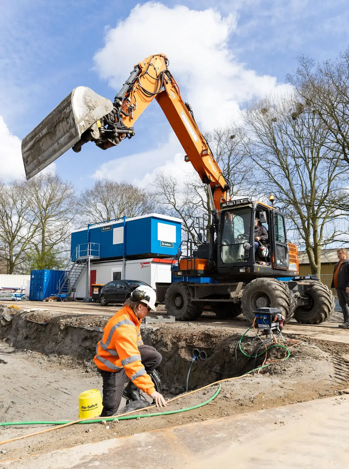 Medewerker aan het werk bij een graafmachine op een bouwterrein
