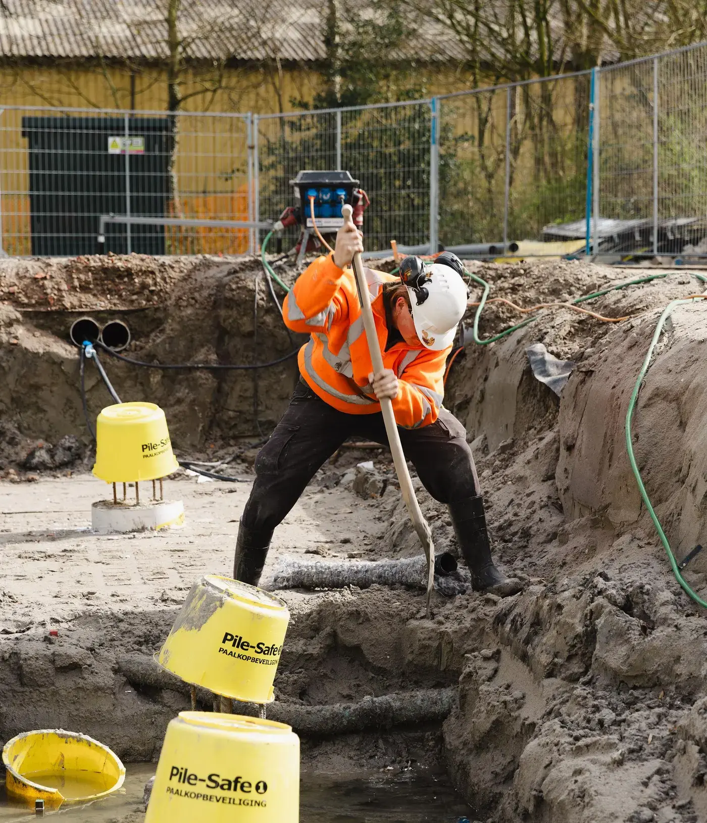 Medewerker aan het werk in een bouwput met gele emmers